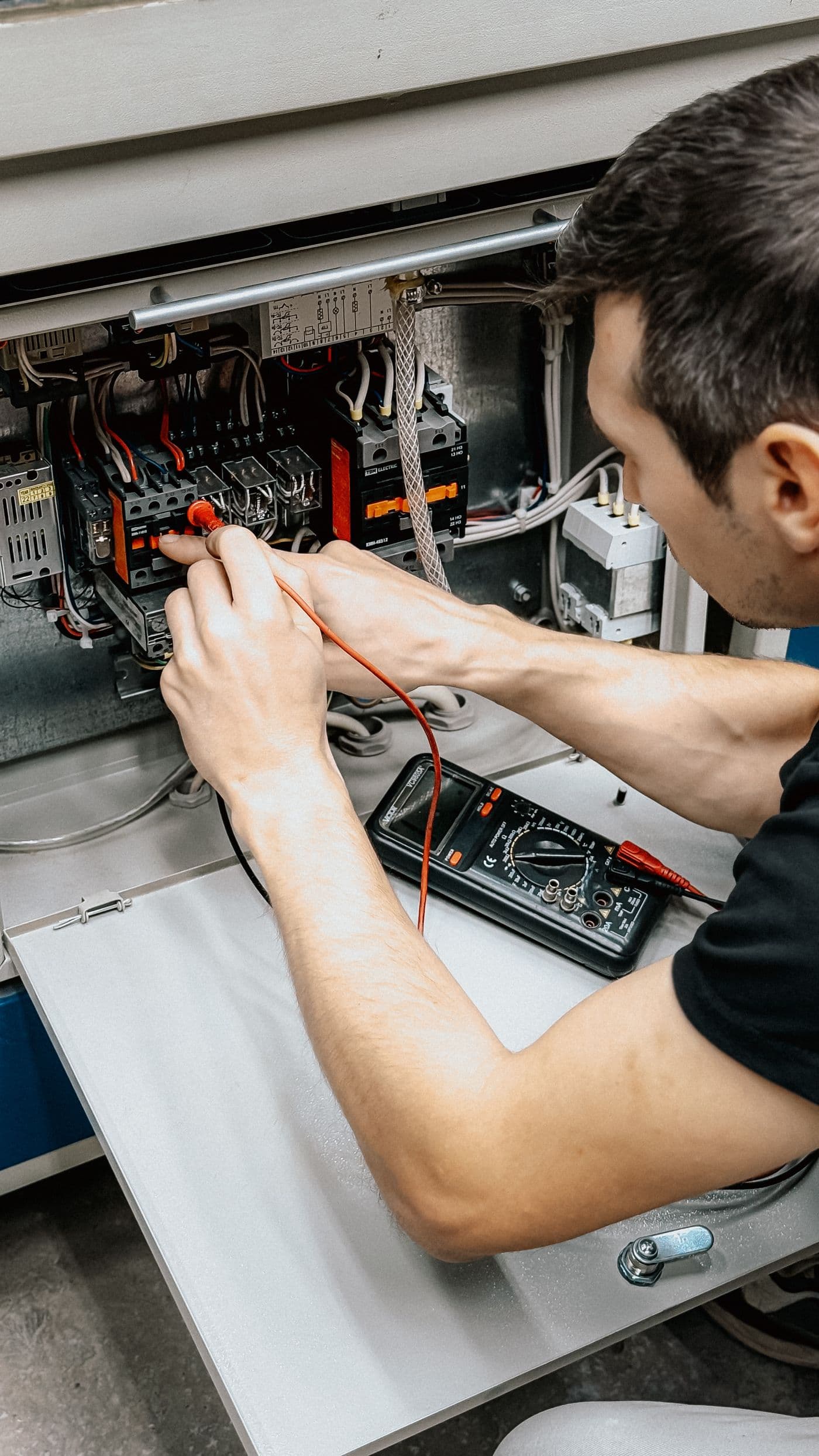 Electrician testing a distribution board with a multimeter